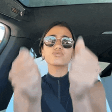 a woman wearing sunglasses is making a funny face in a car
