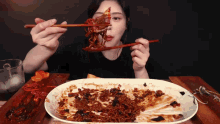 a woman is eating a plate of food with chopsticks ..