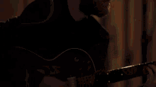 a man in a black coat is singing into a microphone in a recording studio .