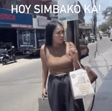 a woman walking down a street with the words hoy simbako ka written on the bottom