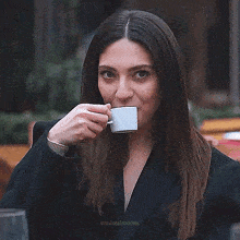 a woman is holding a cup of coffee in her hand .