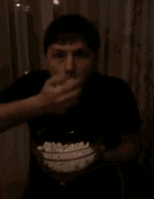 a man is eating popcorn from a bowl with his mouth covered