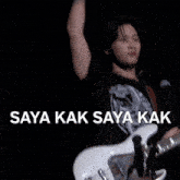 a man playing a guitar with the words saya kak saya kak written above him
