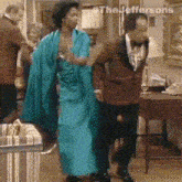 a man in a tuxedo and a woman in a blue dress are dancing in a living room ..