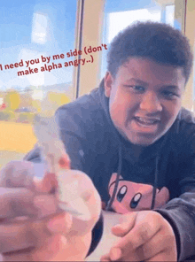 a young man is sitting at a table holding a piece of paper that says `` i need you by me side ''
