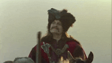 a man with a mustache is riding a horse in a costume