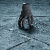 a hand with stitches on it is on a concrete surface with a netflix logo in the corner
