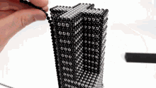 a person is playing with a stack of black and silver magnets .