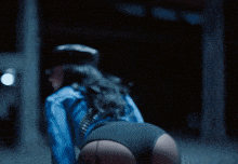 a woman in a blue shirt and black underwear is kneeling down on a chair