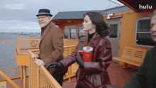 a man in a hat stands next to a woman on a boat that says hulu on the bottom
