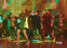 a woman in a green dress is dancing with a man