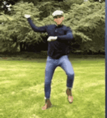 a man in a hat is jumping in the air in a field .