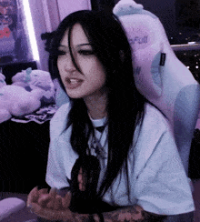 a woman with long black hair is sitting in a white chair .