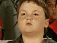 a young boy is sitting in front of a sign that says ' adult swim ' on it