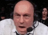 a man wearing headphones and a microphone is making a funny face in front of a woman .
