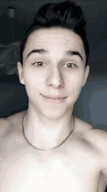 a young man without a shirt is wearing a necklace .