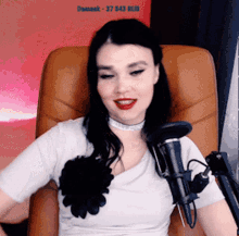 a woman is sitting in a chair with a microphone in front of her and the number 37643 is visible