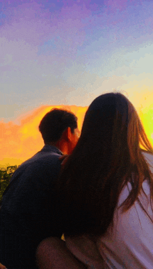 a man and a woman are looking at a sunset together