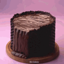 a chocolate cake on a wooden cutting board with mr.cakes written on the bottom right