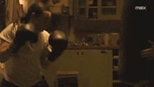 a woman in a white shirt is fighting another woman in a kitchen with a max logo in the background