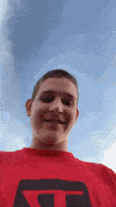 a young man wearing a red t-shirt with the letter g on it