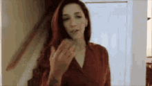 a woman in a red dress is smoking a cigarette in front of a door .