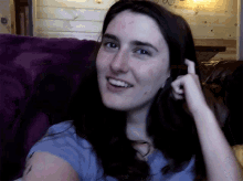 a woman sitting on a couch with her hand on her hair