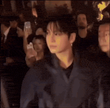 a man is standing in a crowd of people .