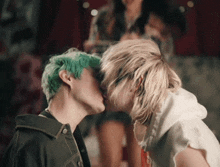 a man with green hair kisses a woman with blonde hair