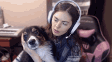 a woman wearing headphones holds a dog