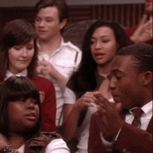 a group of people are sitting in a room and one of them is wearing a red jacket