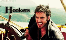 hookers is written on the bottom of a picture of a man behind a steering wheel