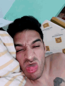 a shirtless man is making a funny face while laying on a bed with a sheet that says orehocar on it