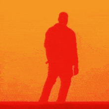 a silhouette of a man standing in front of a red and yellow wall .
