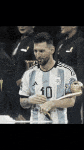 a soccer player with the number 10 on his jersey holds a trophy
