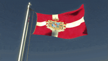 a flag with a coat of arms on it is flying in the wind