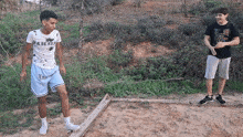 two young men are standing on a wooden beam in the woods .