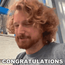 a man with curly hair and a beard says congratulations on his face