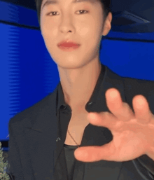 a man in a black suit is making a gesture with his hands