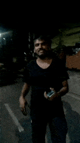 a man in a black shirt is walking down a street