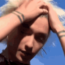 a close up of a person holding their head with a blue sky in the background .