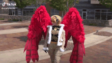 a person in a costume with red feathered wings is walking down the street .
