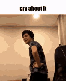 a young man is standing in a room with his hands on his hips and the words cry about it on the bottom .