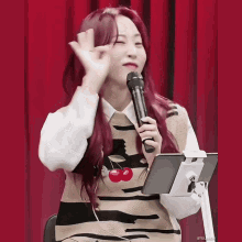 a woman with red hair is holding a microphone in front of a tablet