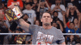 a wrestler wearing a shirt that says the last time is holding a championship belt