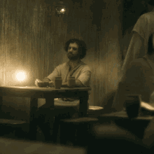 a man sits at a table with two cups and a bowl on it