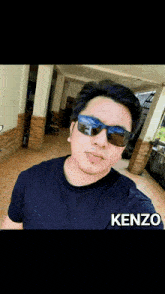 a man wearing sunglasses and a kenzo shirt takes a picture of himself