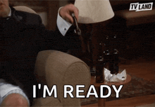 a man in a suit is sitting in a chair holding a bottle of beer and says i 'm ready