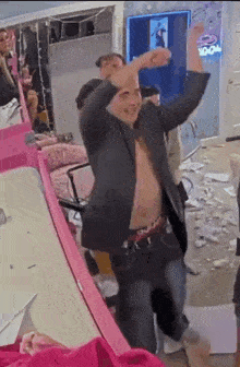 a man without a shirt is dancing in a room with a neon sign that says ' ice cream ' on it