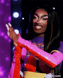 a woman in a pink and purple outfit is smiling and clapping .